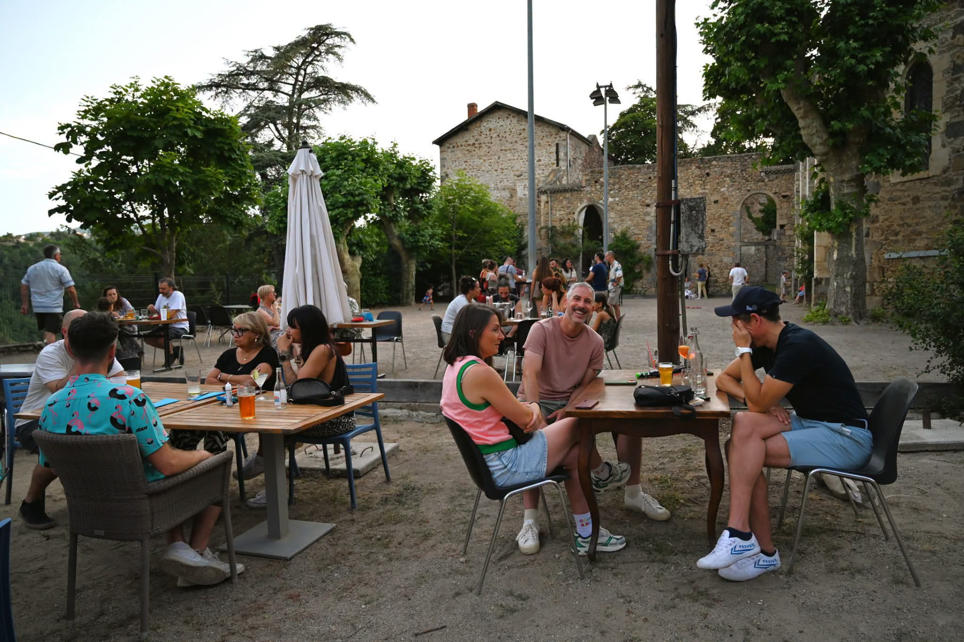 Terrasse animée en soirée d'été face aux ruines en pierre