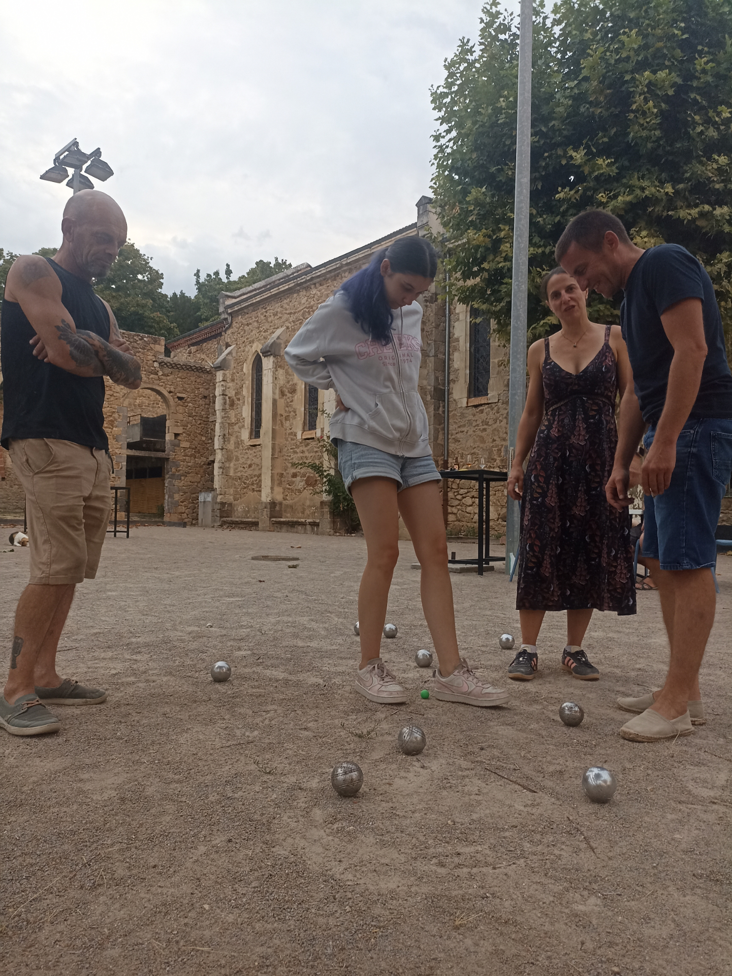 Partie de pétanque conviviale dans la cour du Cercle de Paras, chapelle en arrière-plan